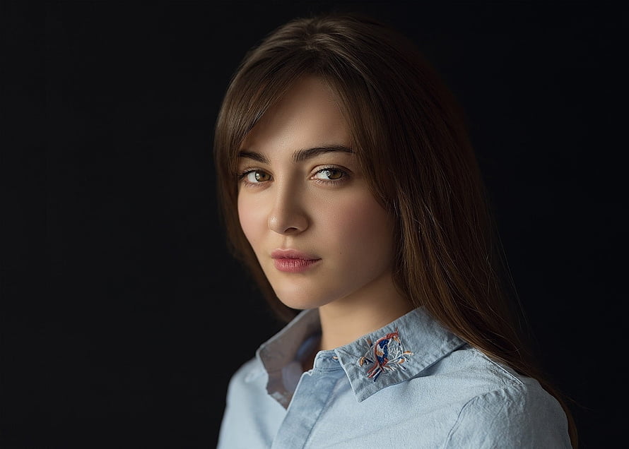 Studio Portrait of a Young Woman in a Light Blue Embroidered Shirt Against a Dark Background HD wallpaper
