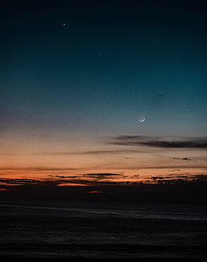 Crescent Moon and Stars Over a Dark Ocean at Dusk with Orange Horizon HD phone wallpaper