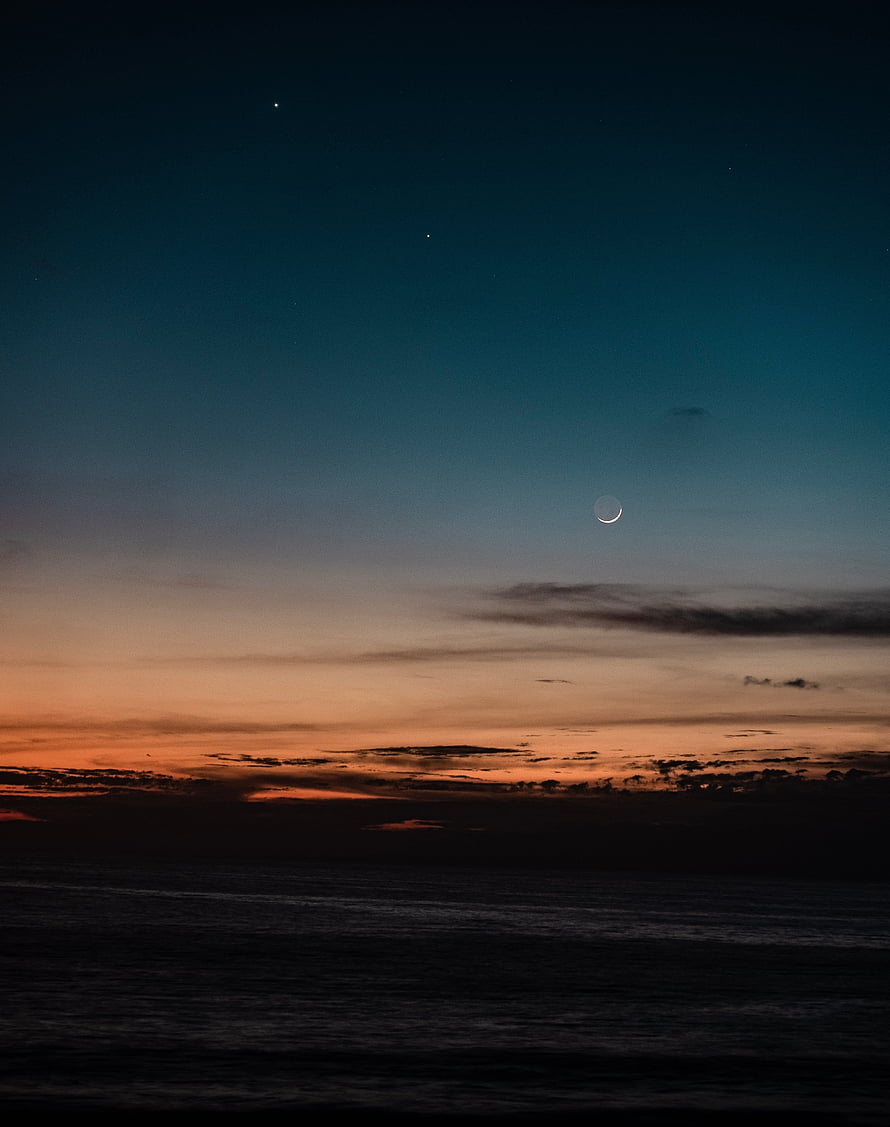 Crescent Moon and Stars Over a Dark Ocean at Dusk with Orange Horizon HD phone wallpaper