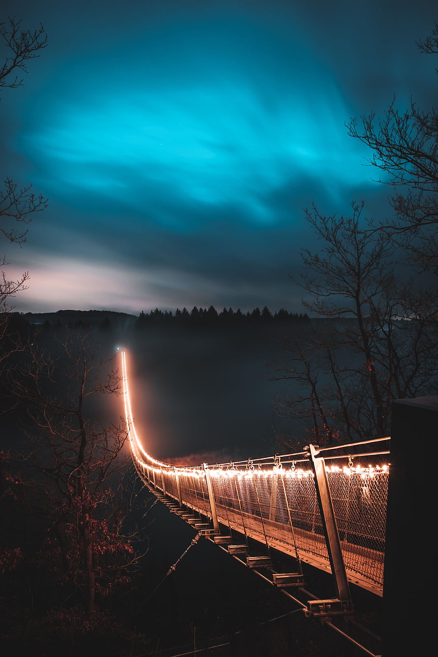 Illuminated Suspension Bridge at Night Under a Glowing Aurora Sky HD phone wallpaper