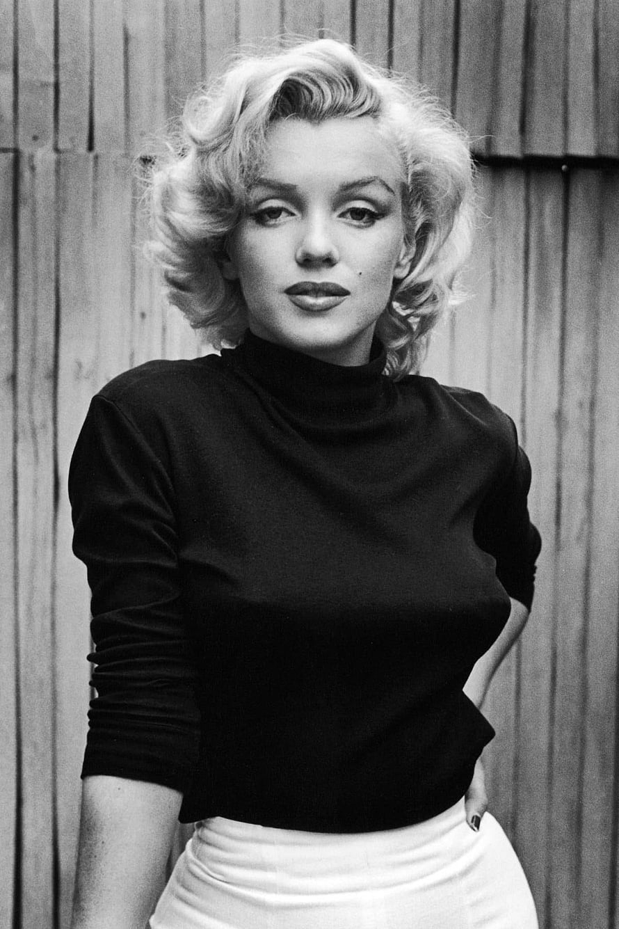Marilyn Monroe in a Black Turtleneck and White Skirt Against a Wooden Fence HD phone wallpaper