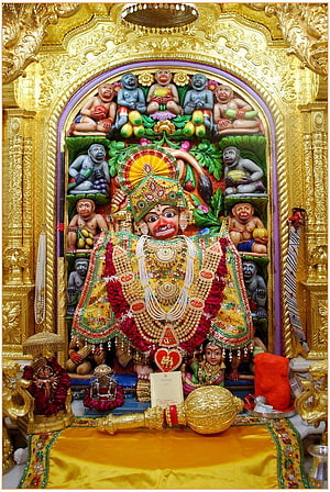 Ornate Hanuman Temple Deity Adorned in Gold and Marigolds with Surrounding Monkey Figures HD phone wallpaper