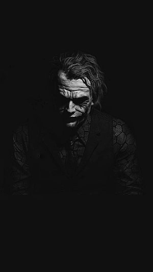Joaquin Phoenix as The Joker in a dark monochrome portrait with textured suit and brooding expression HD phone wallpaper