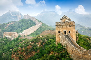 Great Wall of China winding through lush green mountains under a bright blue sky HD wallpaper