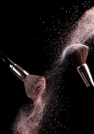 Dramatic Makeup Brushes and Powder Dust Explosion on Black Background HD phone wallpaper