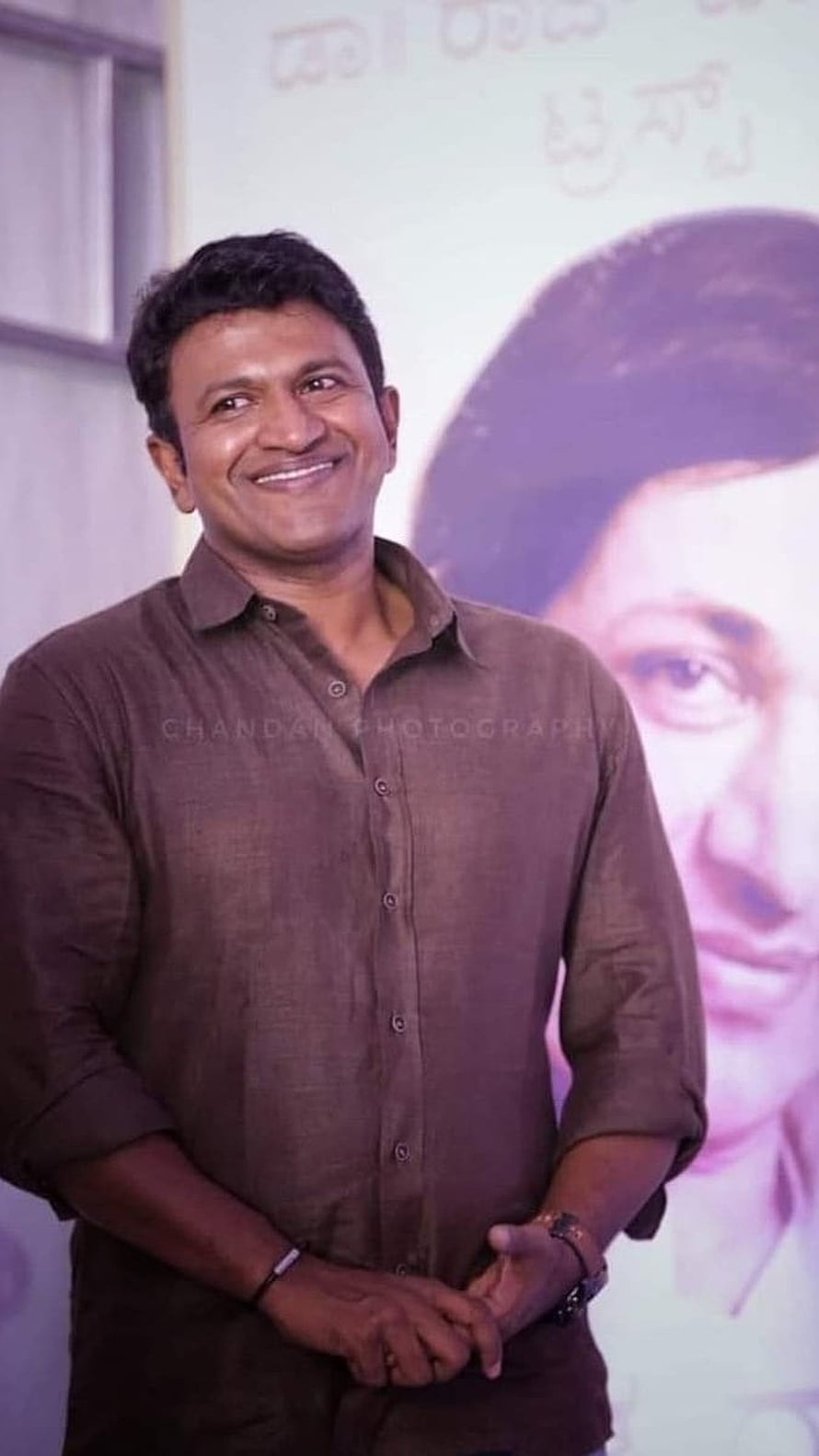 Puneeth Rajkumar smiling in a brown shirt at a Tollywood event HD phone wallpaper