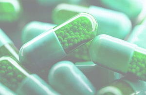 Close-up of green pharmaceutical capsules with visible beads inside HD wallpaper