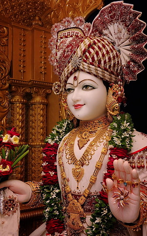 Ornate Swaminarayan Murti Adorned in Gold Jewelry and Floral Garlands HD phone wallpaper