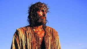 Jesus Christ wearing a crown of thorns in a dramatic cinematic portrait against a clear blue sky HD wallpaper