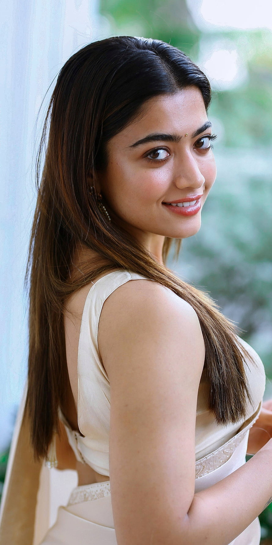 Rashmika Mandanna in a cream sleeveless dress with long dark hair and a soft smile HD phone wallpaper