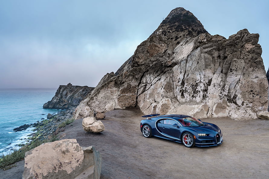 Blue Bugatti Chiron Parked on Coastal Cliff with Rocky Outcrop and Ocean View HD wallpaper