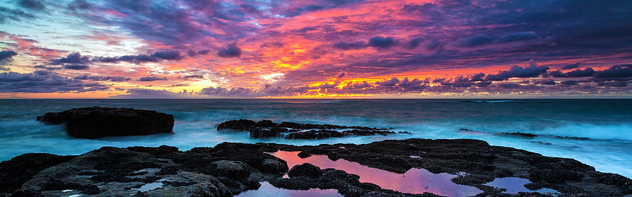Vivid Coastal Sunset Over Rocky Shoreline With Turquoise Water and Dramatic Clouds HD wallpaper
