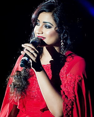 Shreya Ghoshal performing live on stage in a vibrant red embroidered outfit HD phone wallpaper
