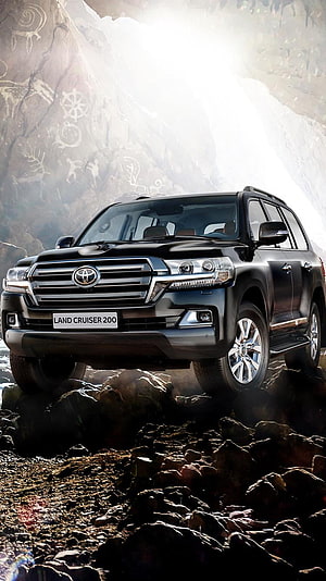 Black Toyota Land Cruiser 200 SUV on Rocky Terrain with Ancient Rock Art Background HD phone wallpaper