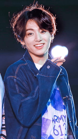Jungkook from BTS smiling on stage in a denim jacket with ARMY 613 banner HD phone wallpaper