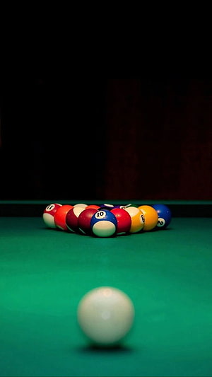 Billiard balls racked on a green felt table with a white cue ball in the foreground HD phone wallpaper
