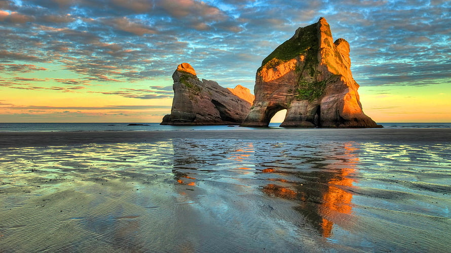 Dramatic Coastal Rock Arch at Golden Hour with Mirror-Like Beach Reflections HD wallpaper