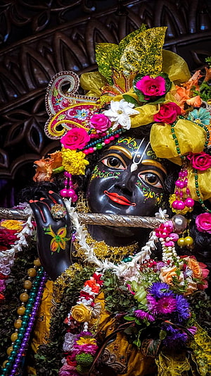 Ornate Krishna Murti Adorned With Vibrant Flowers And Jewels HD phone wallpaper