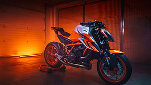 KTM 1290 Super Duke R EVO sport bike in orange and black under dramatic garage lighting HD wallpaper