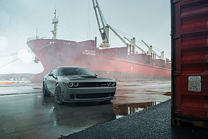 Gray Dodge Challenger SRT parked on a wet dock in front of a large red cargo ship HD wallpaper