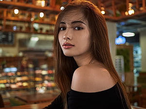 Young woman with long brown hair in an off-shoulder black top at a cafe HD wallpaper