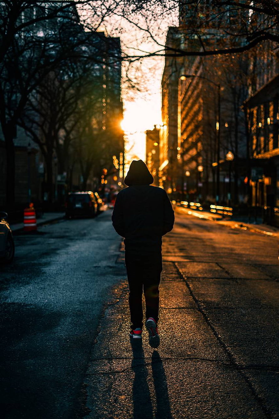 Silhouette of a man walking down a city street at golden hour with long shadows HD phone wallpaper