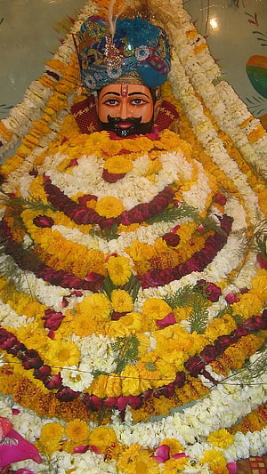 Khatu Shyam Ji adorned in vibrant marigold and rose flower garlands with ornate blue crown HD phone wallpaper