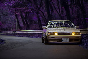 Classic JDM Sedan on a Winding Road with Purple Cherry Blossoms HD wallpaper