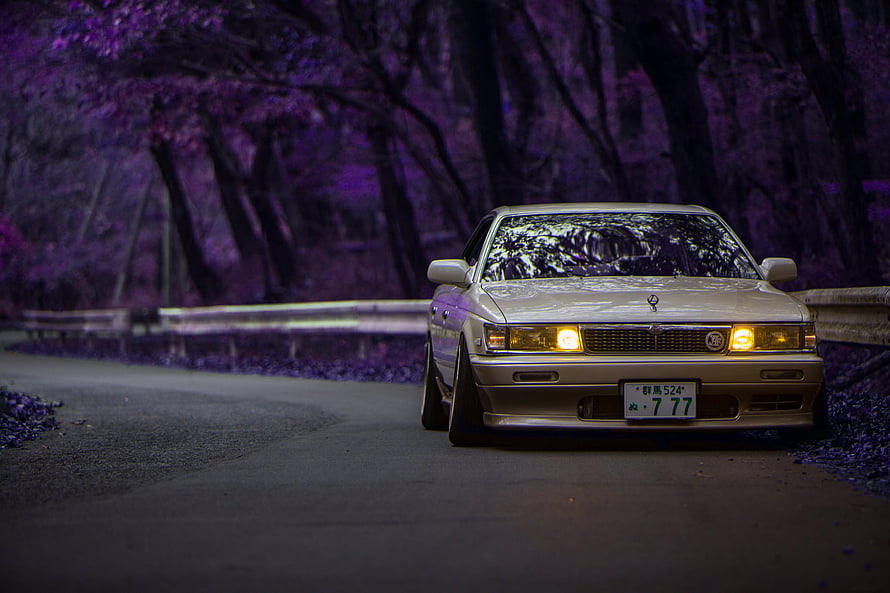 Classic JDM Sedan on a Winding Road with Purple Cherry Blossoms HD wallpaper