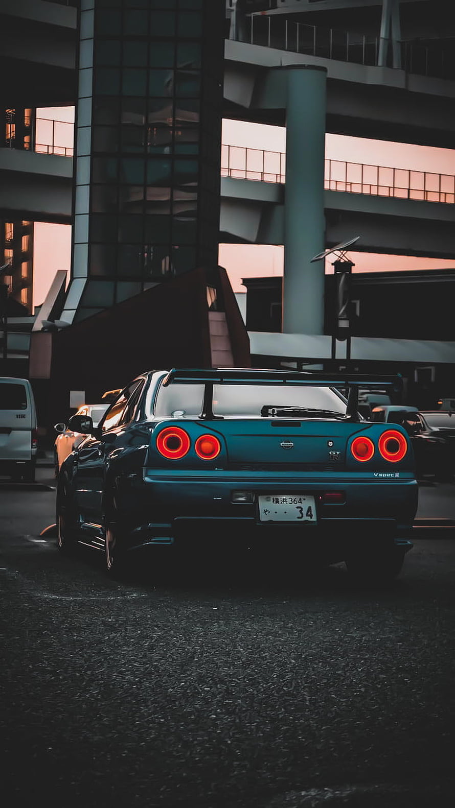 Rear View of a Blue Nissan Skyline GT-R R34 Parked in an Urban Setting at Dusk HD phone wallpaper