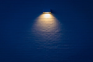 Warm Sconce Light on Dark Blue Brick Wall at Night HD wallpaper