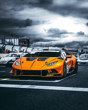 Orange Lamborghini Huracan GT3 race car on the track under a dramatic stormy sky HD phone wallpaper