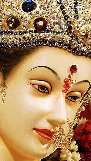 Close-up of Durga Maa statue adorned with jeweled crown and floral garlands HD phone wallpaper