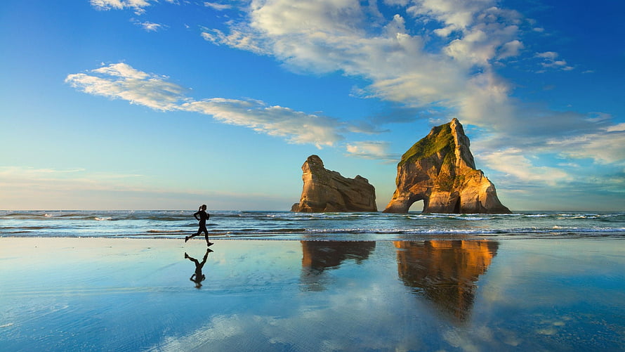 Runner on a Wet Beach with Dramatic Sea Stacks and Mirror Reflections HD wallpaper