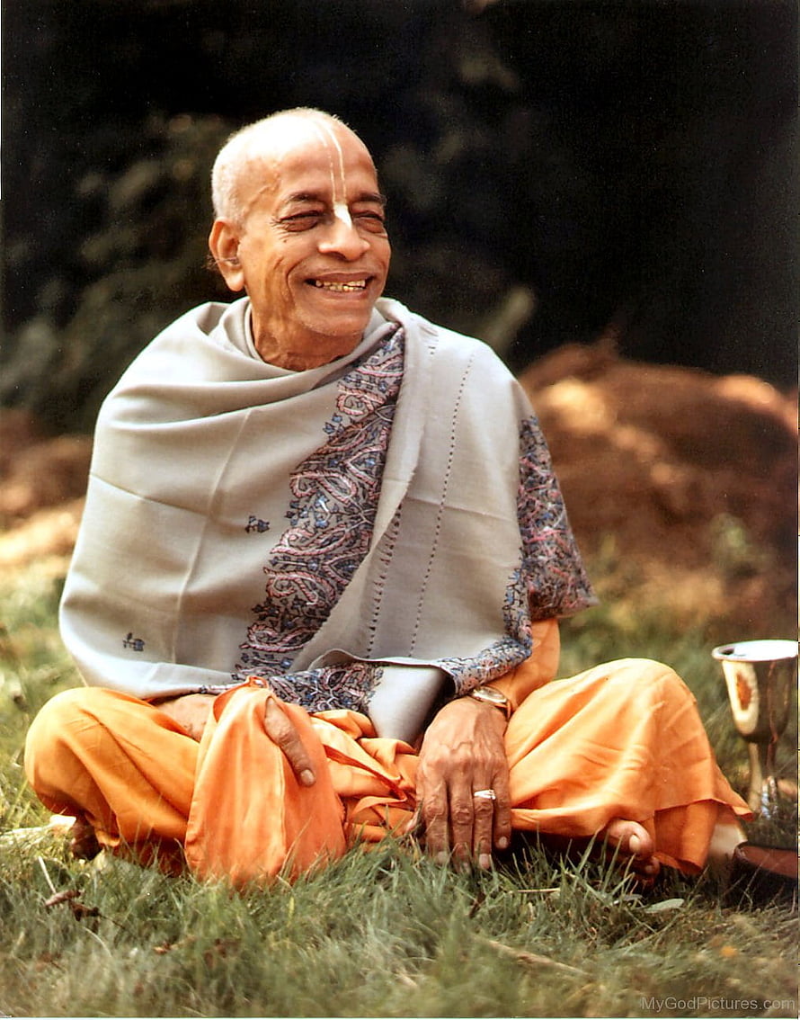 A. C. Bhaktivedanta Swami Prabhupada seated in nature wearing traditional orange robes and a shawl HD phone wallpaper