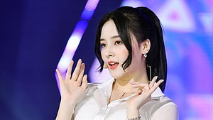 Nancy from Momoland performing on stage in a white blouse with vibrant blue and purple lighting HD wallpaper