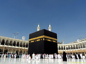 The Sacred Kaaba in Mecca with Pilgrims Performing Tawaf Under a Clear Blue Sky HD wallpaper