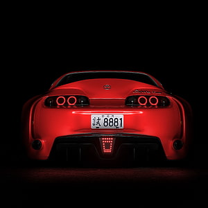 Rear View of a Red Toyota Supra with Glowing Taillights Against a Black Background HD phone wallpaper