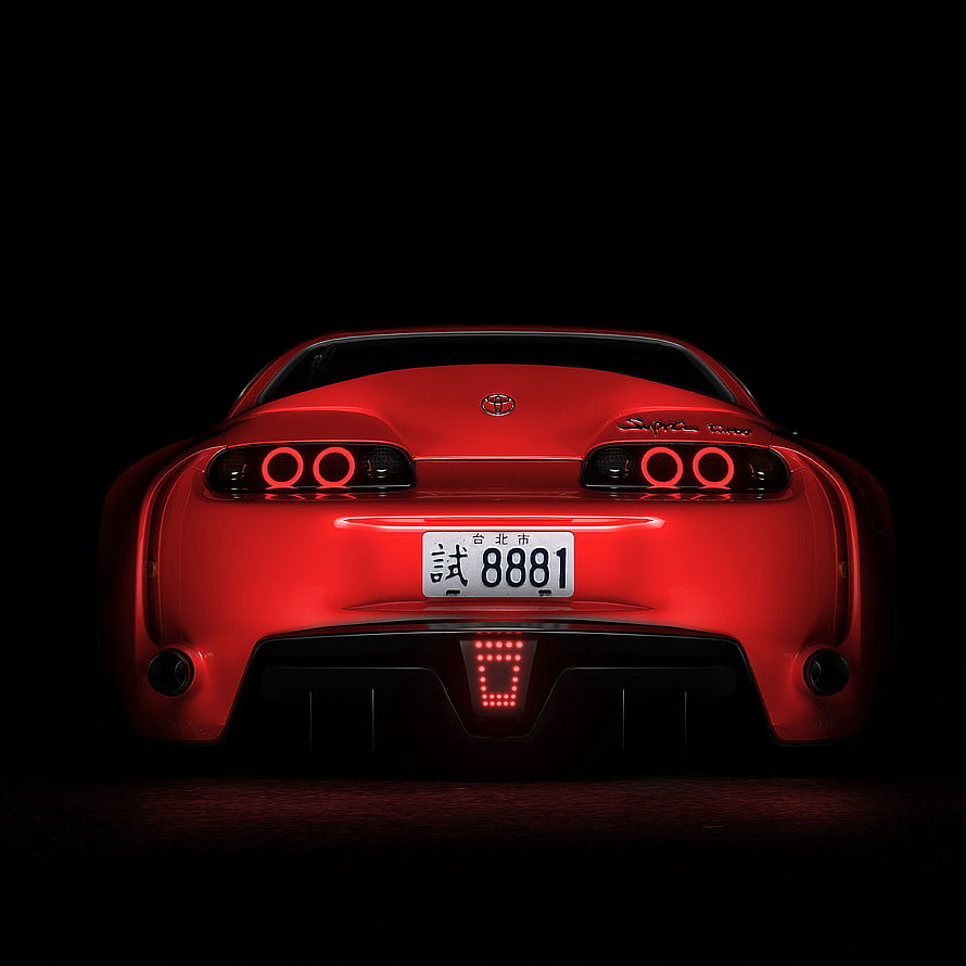 Rear View of a Red Toyota Supra with Glowing Taillights Against a Black Background HD phone wallpaper
