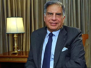 Ratan Tata in a dark suit and blue tie seated in a formal office with a brass lamp HD wallpaper