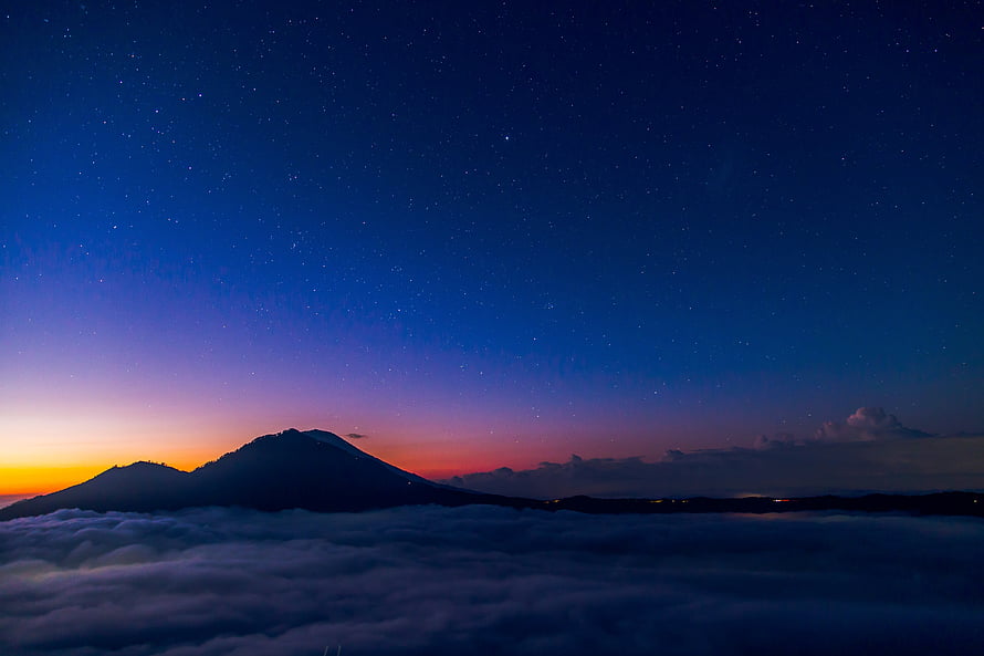 Volcanic Peak Rising Above Sea of Clouds Under a Starry Twilight Sky HD wallpaper