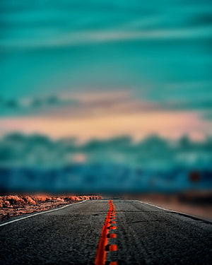 Empty Desert Highway Stretching Toward a Teal and Orange Sunset Horizon HD phone wallpaper