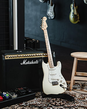 White Electric Guitar Leaning Against Marshall Amplifier in Studio Setting HD phone wallpaper