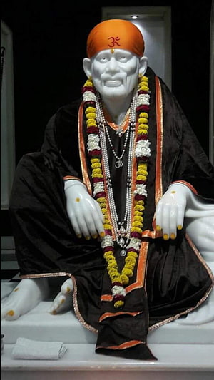 Sai Baba Statue in Black Robe with Orange Turban and Marigold Garland HD phone wallpaper