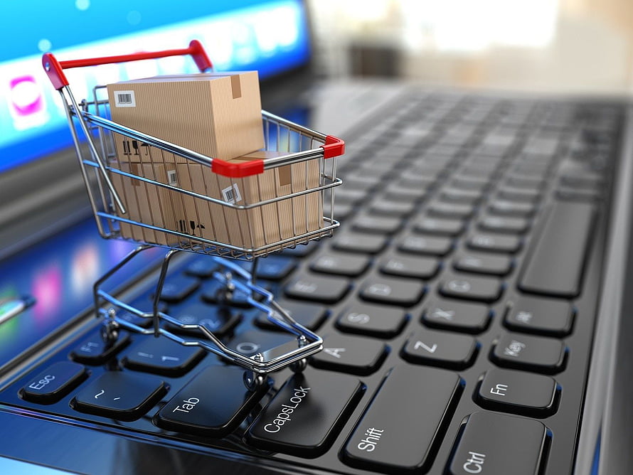 Miniature shopping cart with cardboard boxes on a laptop keyboard representing online retail HD wallpaper