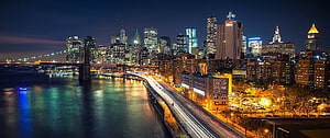 New York City Skyline at Night with Brooklyn Bridge and Long Exposure Traffic Trails HD wallpaper
