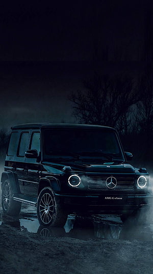 Black Mercedes-Benz G-Class AMG SUV with glowing headlights in a dark misty night scene HD phone wallpaper