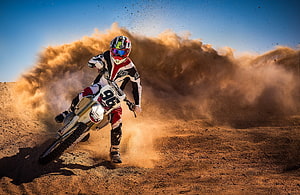 Motocross Rider Kicking Up Dust Cloud on Dirt Track HD wallpaper