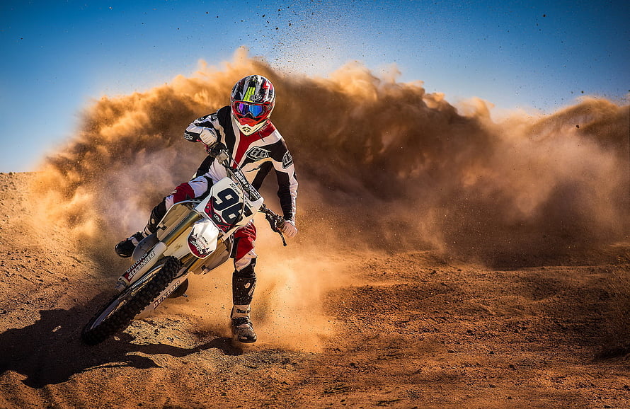 Motocross Rider Kicking Up Dust Cloud on Dirt Track HD wallpaper