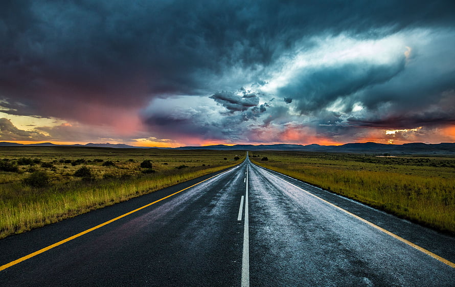 Dramatic Storm Clouds Over a Wet Highway at Sunset in the Open Plains HD wallpaper